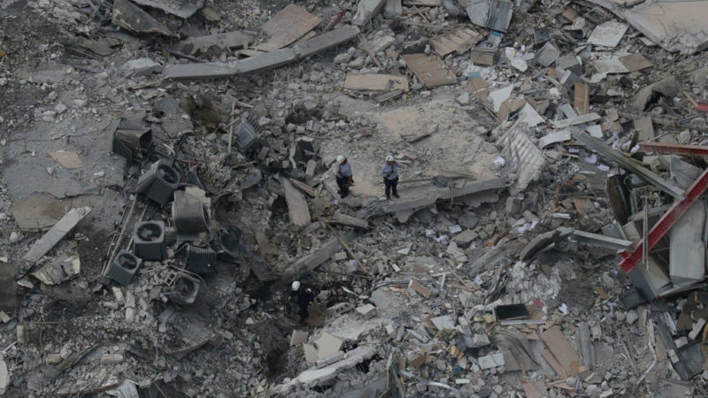 aerial view of two rescue workers standing in the rubble pile