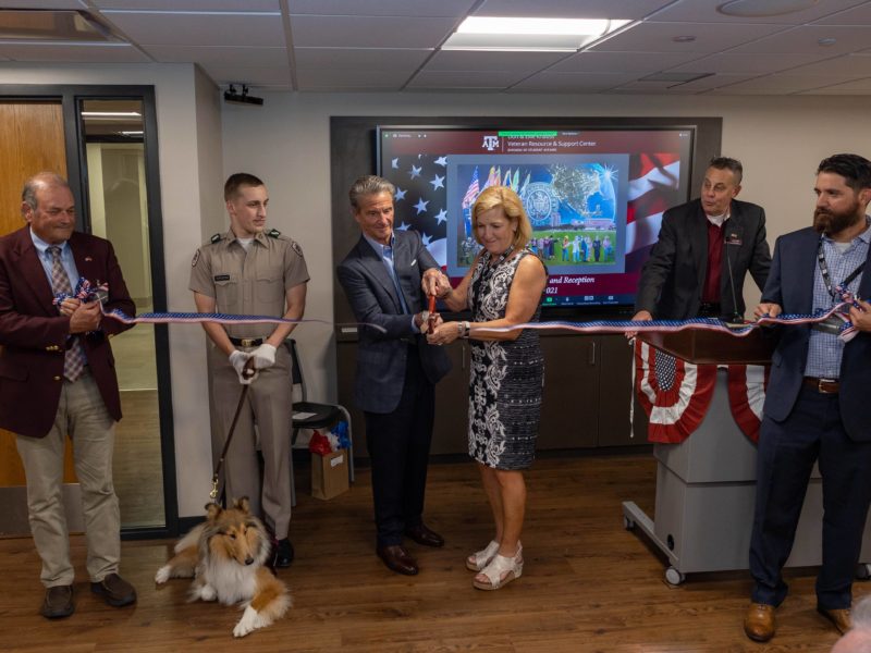 ellie and don knauss cut a ribbon as reveille and handler, others look on