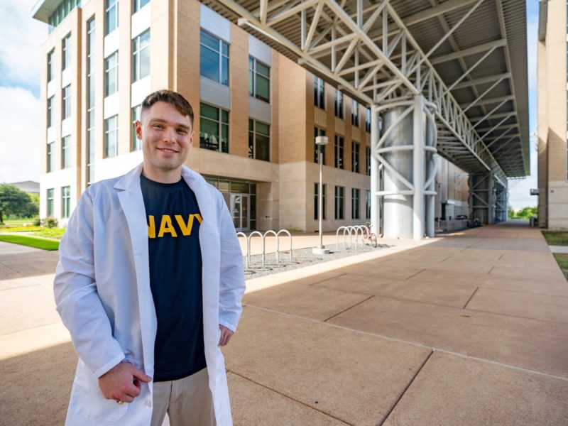 portrait of andrew chapman in medical coat standing outside agrilife building