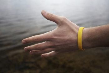 close up of a person holding their hand out with a yellow wristband on their wrist