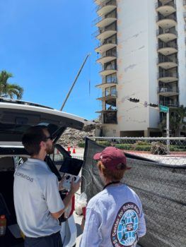 photo of murphy next to a man operating a drone with the condo in the background