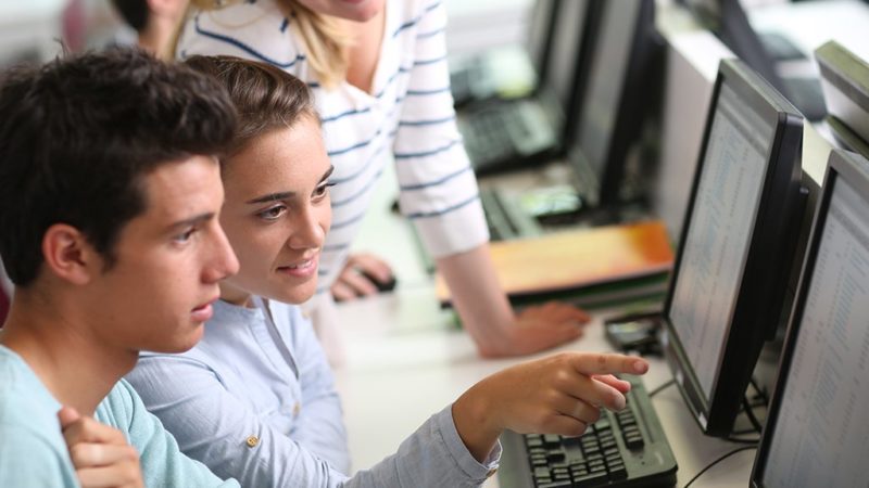 a photo of young people looking at a computer