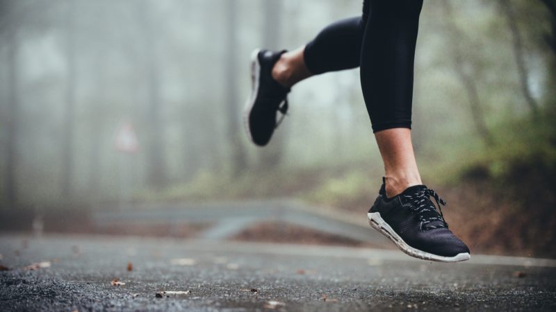 view of a woman's legs running on a road on a foggy day