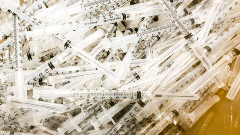 vaccine syringes sit in a pile