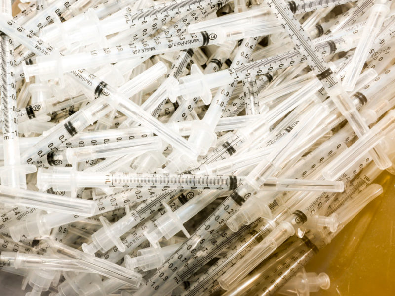 vaccine syringes sit in a pile
