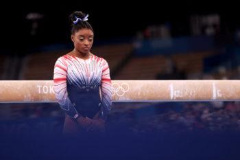 portrait of simone biles standing in front of the balance beam