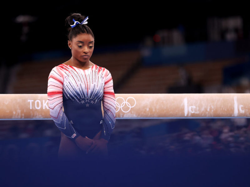 portrait of simone biles standing in front of the balance beam