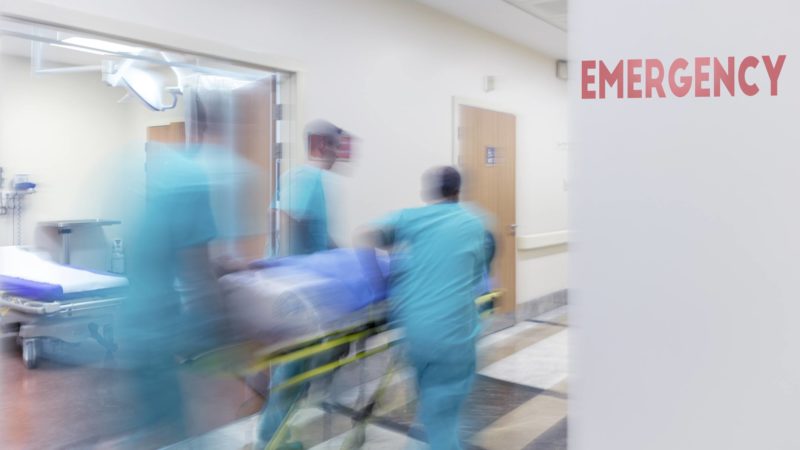blurred image of doctors wheeling patient through hospital emergency room