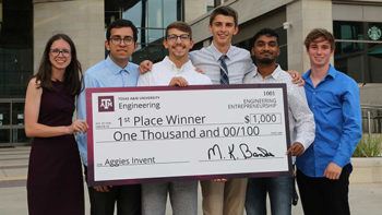 a group of students pose with an oversized check that says 1st place winner, one thousand dollars