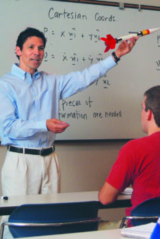 hurtado at the front of a classroom speaking on front of a white board covered in equations