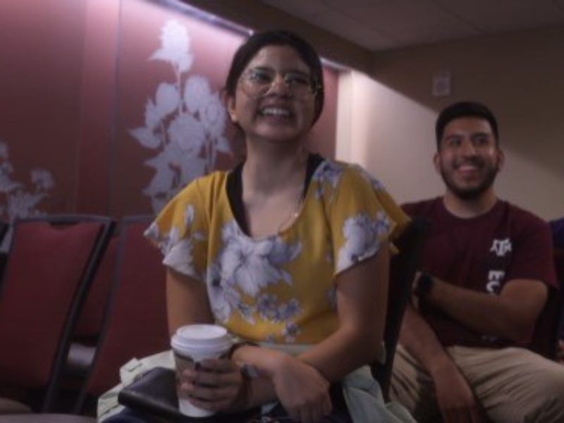 video still of female student and two male students sitting in a meeting room while talking