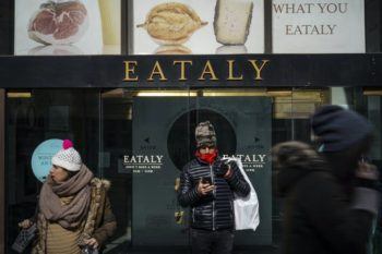 people stand under a sign advertising the restaurant Eataly