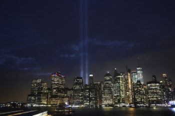 the NYC skyline at night with spotlights showing where the twin towers stood