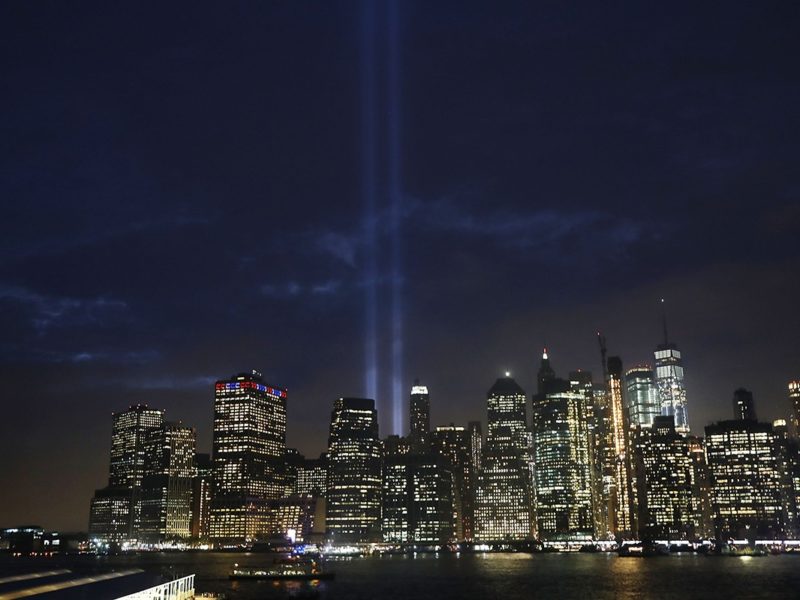the NYC skyline at night with spotlights showing where the twin towers stood