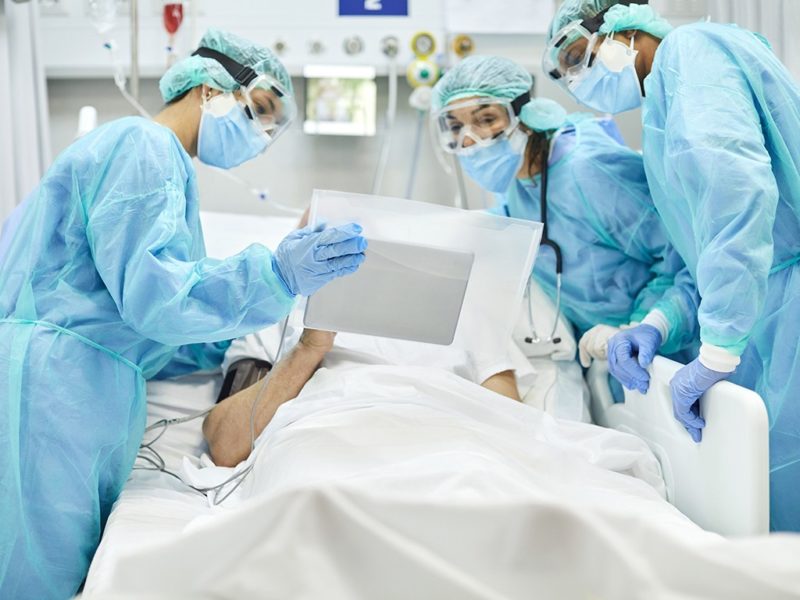 a photo of healthcare workers talking to a patient in a hospital room