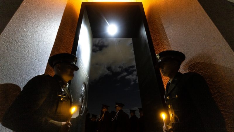 two cadets stand in a glowing portal with the moon shining through