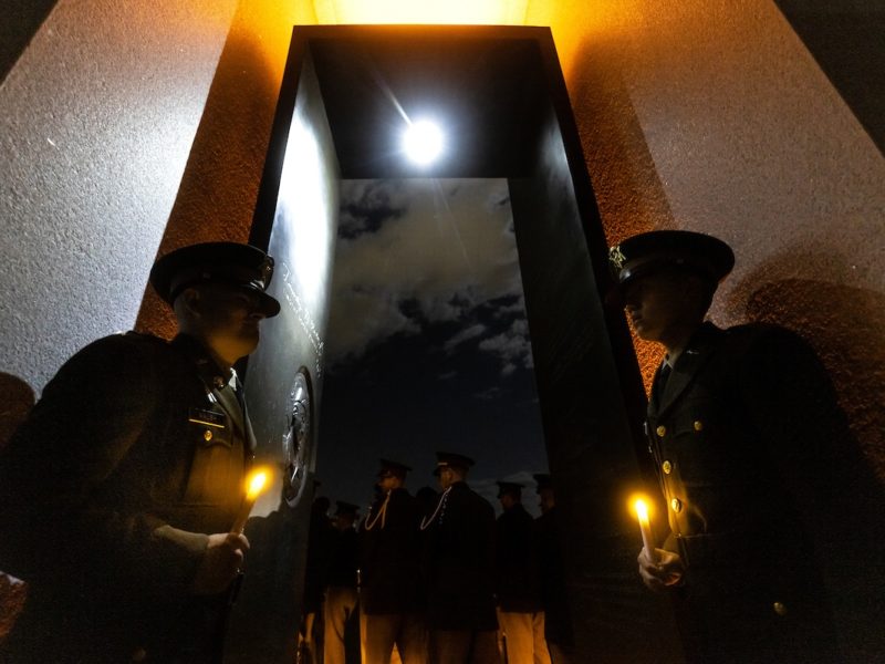 two cadets stand in a glowing portal with the moon shining through