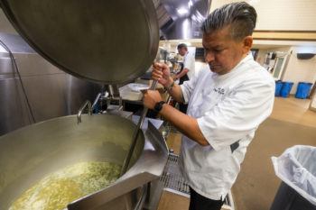 chef stirring large pot of gravy in kitchen
