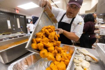 man pours tray full of orange yams