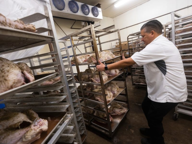chef pulling racks of turkeys through kitchen