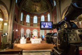 a digital camera is placed in the aisle of a catholic church for an online service