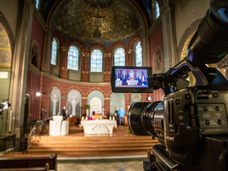a digital camera is placed in the aisle of a catholic church for an online service