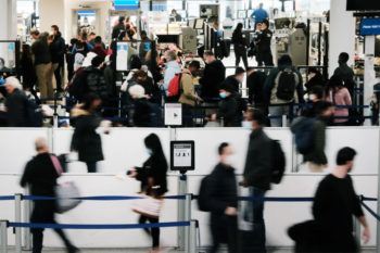 travelers walk through the security line at a busy airport terminal