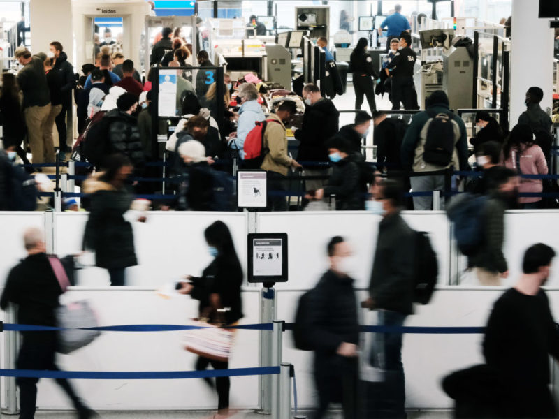 travelers walk through the security line at a busy airport terminal