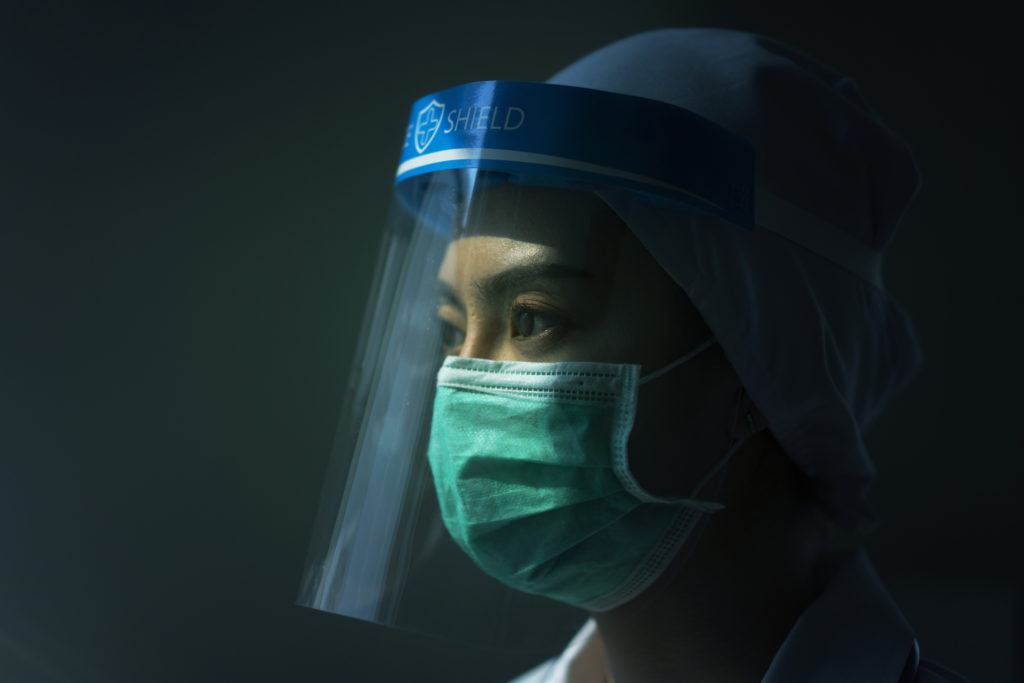 closeup of nurse wearing face mask and plastic face shield in profile