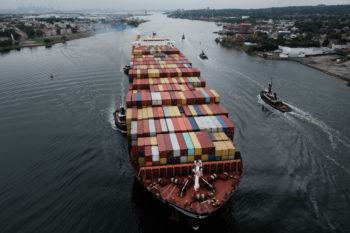 a cargo ship filled with shipping containers passes through a port