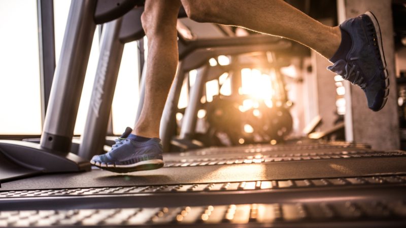 legs of man jogging on a treadmill in a gym
