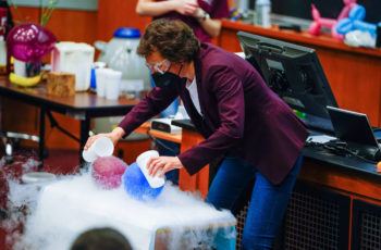 professor standing in front of a lecture hall preforming an experiment that creates billowing white clouds