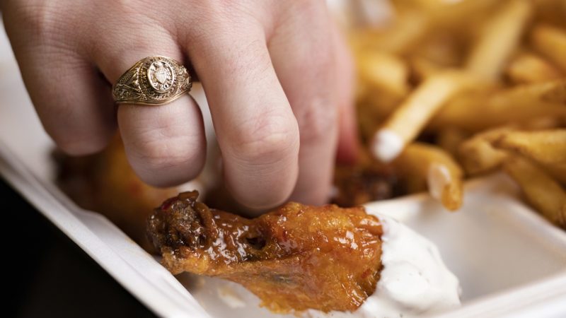 hand wearing aggie ring dunking a chicken wing into ranch dressing