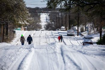 pedestrians walking on a hilly road covered in snow in austin texas