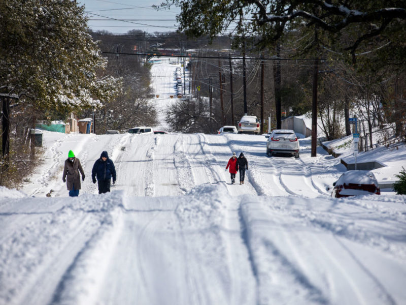 pedestrians walking on a hilly road covered in snow in austin texas