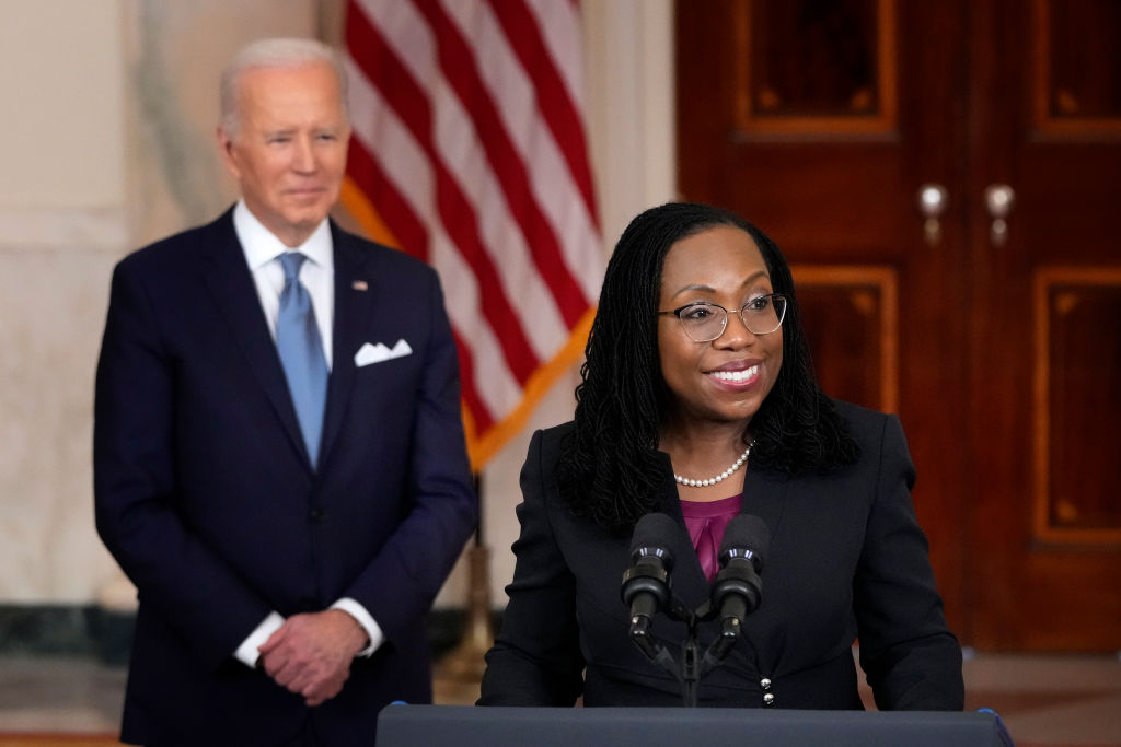 brown jackson speaking at podium while biden looks on