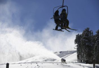 silhouttes of two people on a ski lift on a snowy mountain