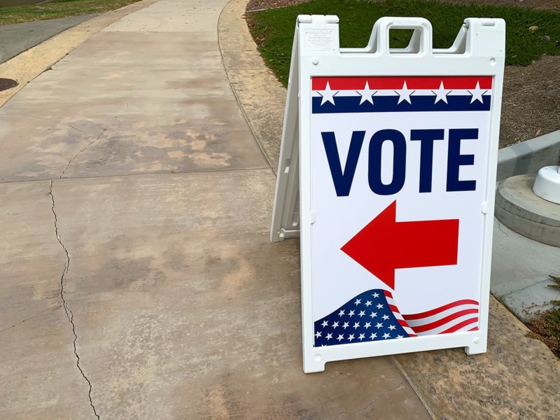 Red, white and blue sign with an arrow indicating where to go to cast or leave a ballot.