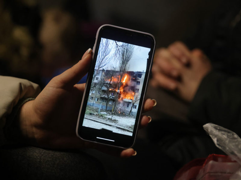 a photo of a person holding an iphone with an image of a burning building