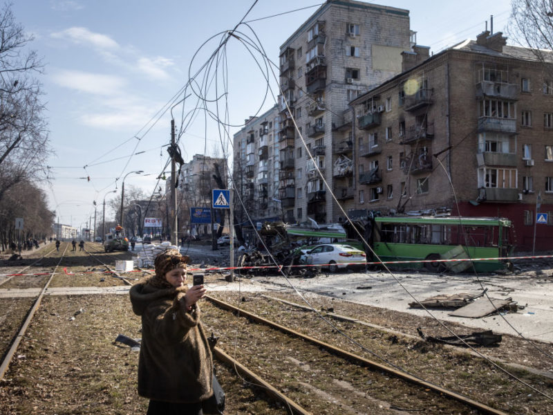A woman takes a selfie in front of a damaged residential apartment block caused after a Russian rocket was shot down by Ukrainian air defences