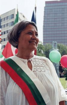 A photo of a woman wearing a red, green and white sash and smiling