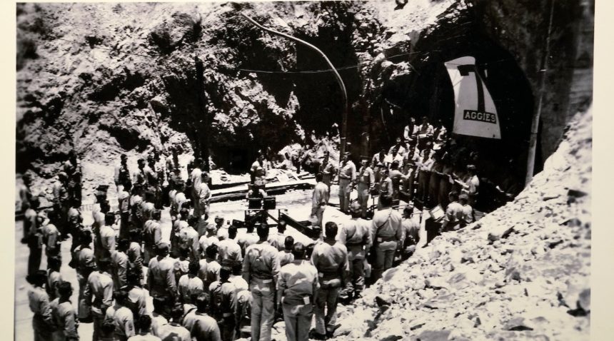 a black and white photo of a group of men standing in front of a tunnel