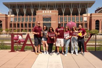 a family poses near Kyle Field during Family Weekend