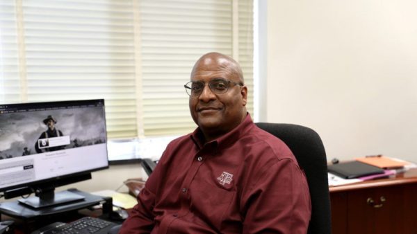 leroy dorsey sitting at a desk with a computer monitor in the background showing a photo of theordore roosevelt