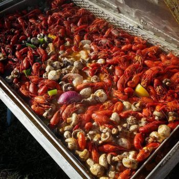 a photo of crawfish being boiled along with mushrooms, onions, celery and lemons