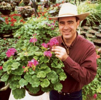 a photo of a man in a hat holding a potted plant and smiling