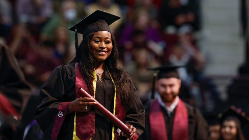 graduates cross the stage at Reed Arena