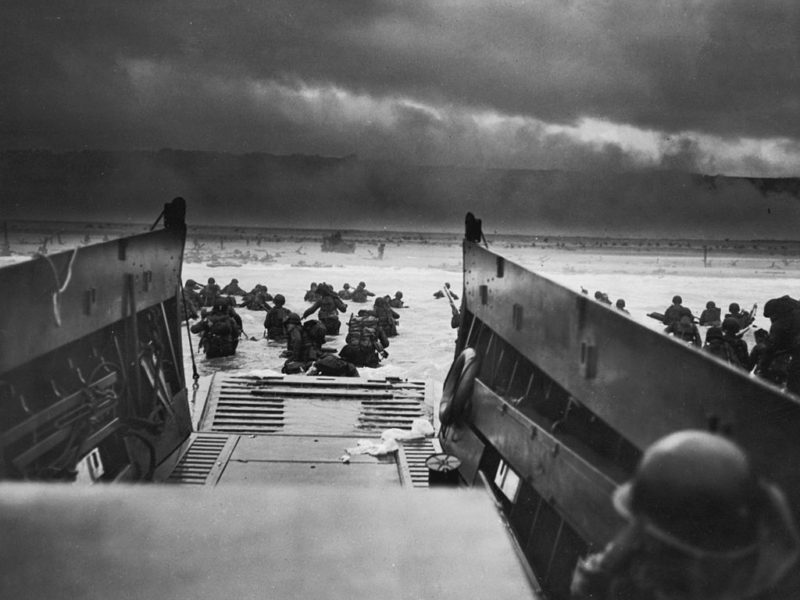 black and white photos showing troops exiting a boat into the waters of normandy beach