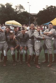a photo of a group of cadets on the drill field, with one female cadet in the center