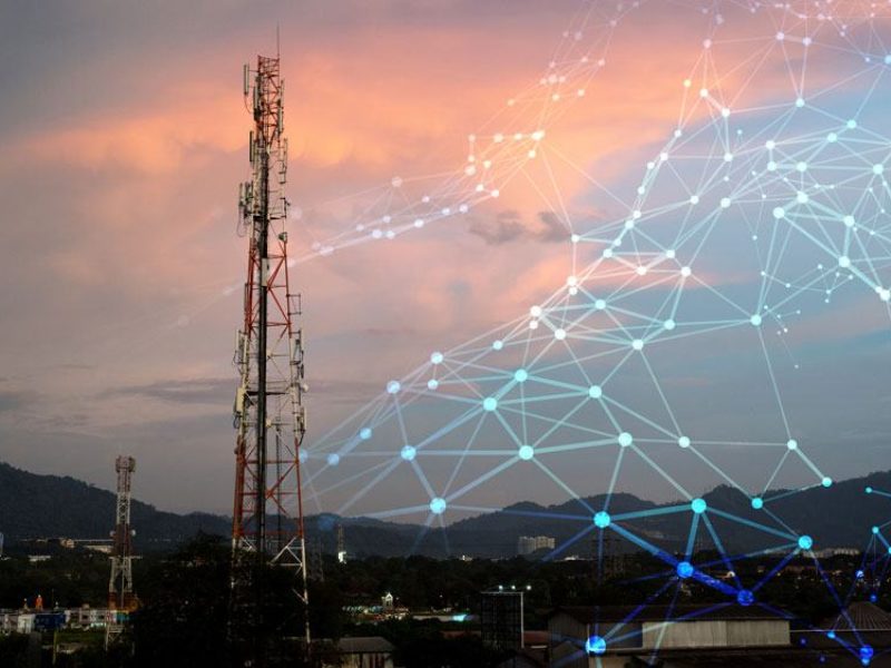 Artist's concept illustration of a wireless network layered over a photo of a cell phone tower against a sunset.